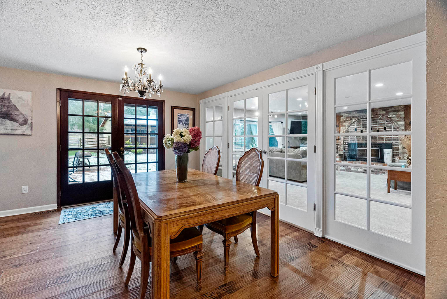 Spacious dining room with hand-scraped floors and French doors to back deck